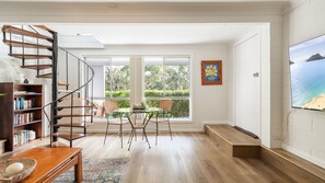 Un interior moderno con una escalera espiral, un comedor con vistas y una gran pantalla de televisión.