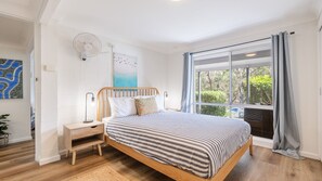 Una camera da letto con un letto, un comodino, una lampada, opere d'arte alle pareti e una finestra con tende.