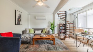 Una sala de estar con sofá, mesa de centro y escalera de caracol.
