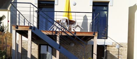 A two-story house with a balcony, a staircase, and a yellow umbrella.