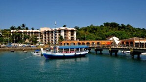 A waterfront hotel with a large building, a dock with boats, and a bridge. - House on Itaparica Island - Ponta de Areia Beach (Itaparica)