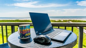 A laptop, a mouse, and a can on a table with a view of the ocean. - Sunny beachfront condo (Galveston)