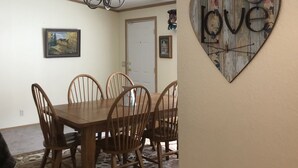 A dining area with a wooden table and chairs, a chandelier, and a heart-shaped wall decoration with the word "love".
