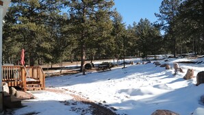 A snowy outdoor area with a wooden deck, large rocks, and a clear sky.