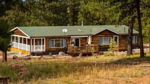 A cabin with a porch, a deck, and a satellite dish.