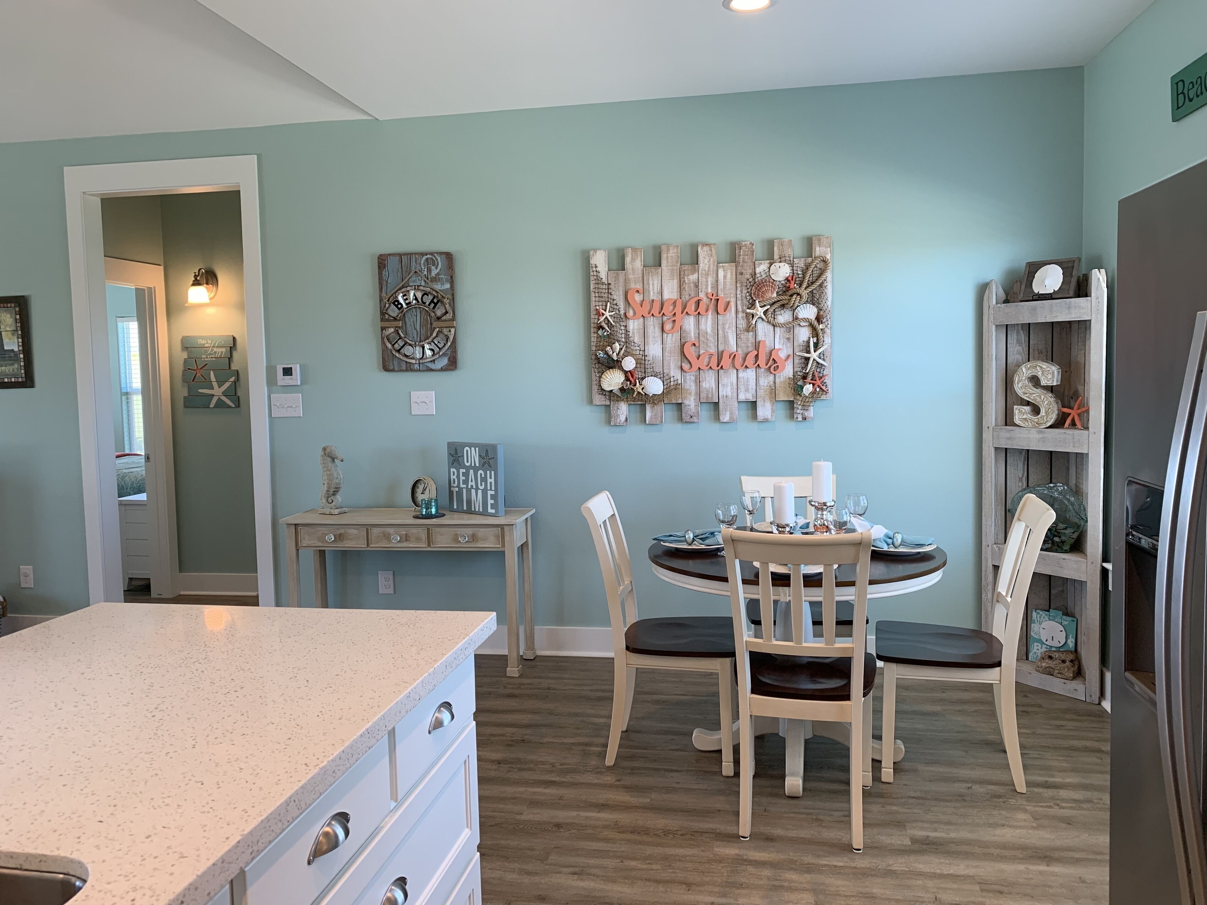 A dining area with a round table set for four, a wooden wall decor, and a bookshelf with a 'S' shaped shelf.