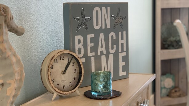 A wooden dresser with a vintage clock, a decorative glass, and a sign that reads "ON BEACH TIME". - You've earned the right to enjoy the best! (Bolivar Peninsula)