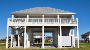 A two-story building with a covered patio area and a balcony. - You've earned the right to enjoy the best! (Bolivar Peninsula)