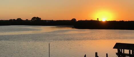 A sunset over a calm lake with a wooden dock extending into the water.