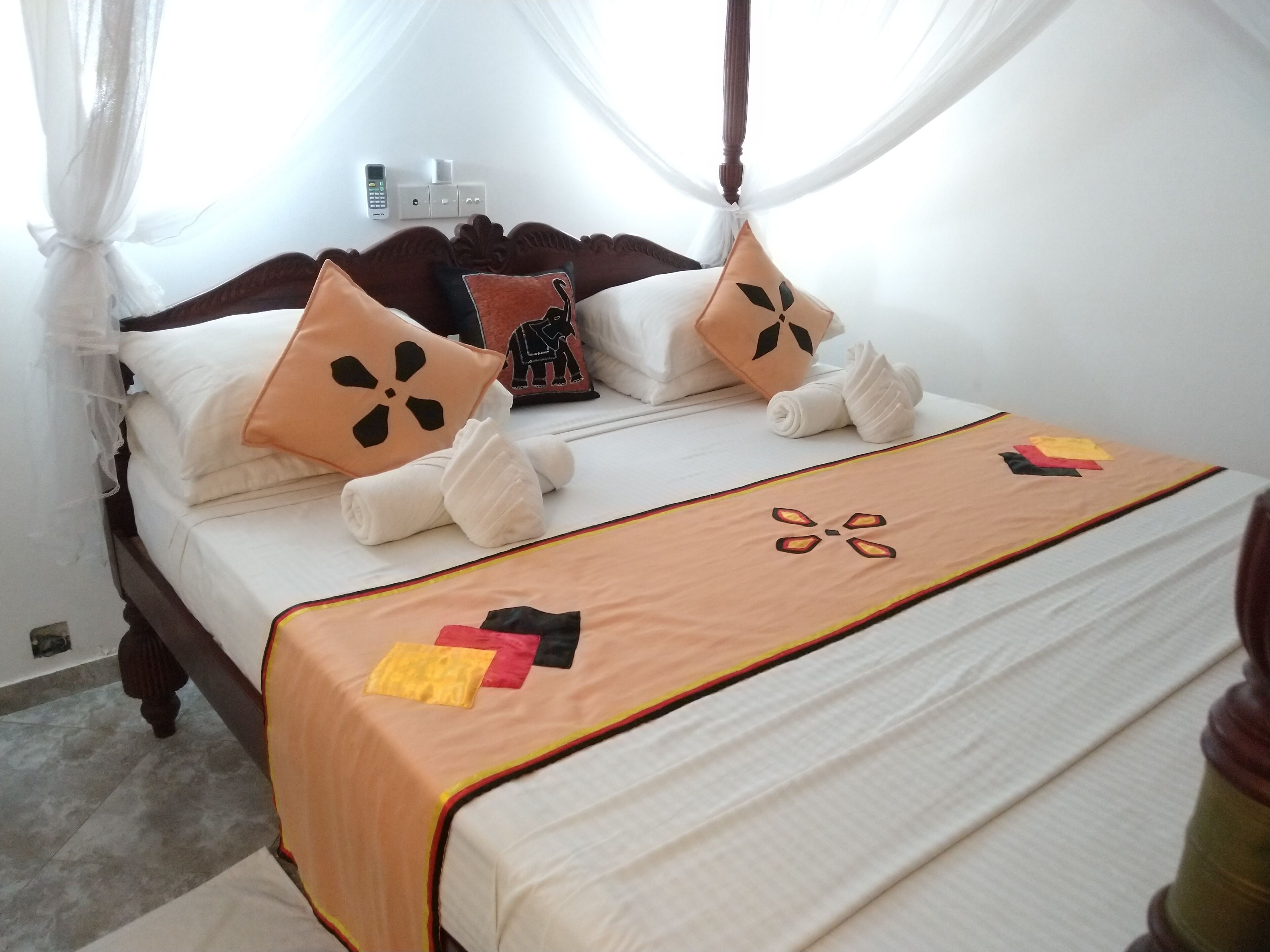 A neatly made bed with a canopy, white linens, and decorative pillows.