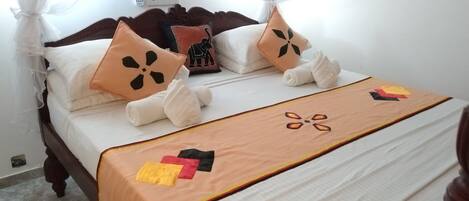 A neatly made bed with a canopy, white linens, and decorative pillows.