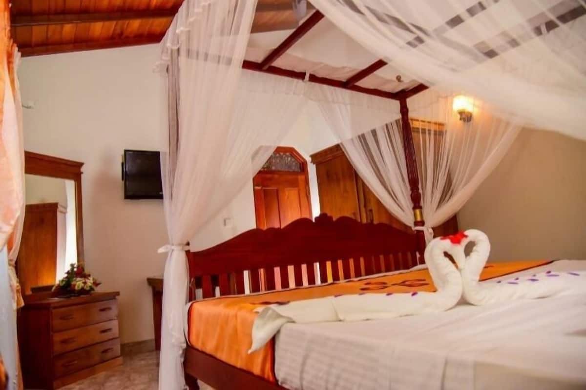 Quarto com cama de dossel, cabeceira de madeira e um cisne decorativo na cama.