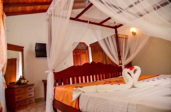 Un dormitorio con cama con dosel, cabecera de madera y un cisne decorativo sobre la cama.