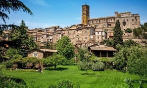A historic town with medieval architecture, including a prominent tower and closely packed buildings. - B&B Notti d'Oriente (Sutri)