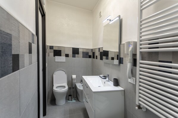 A modern bathroom with a toilet, bidet, sink, and mirror. - B&B Notti d'Oriente (Sutri)