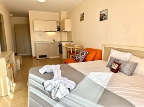 Relax in this stylish room with a large bed, seating area, and kitchenette, perfect for a comfortable stay.