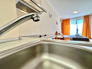 Enjoy a restful stay in this stylish room featuring a bed, a wooden table, and a stainless steel sink.
