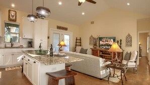 A spacious kitchen with a large island, white cabinetry, and a farmhouse sign.