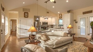 A spacious living room with a large sofa, a coffee table, and a dining area with a kitchen in the background.