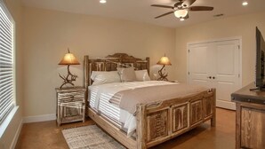 A bedroom with a wooden bed, two bedside lamps, a ceiling fan, and a door.