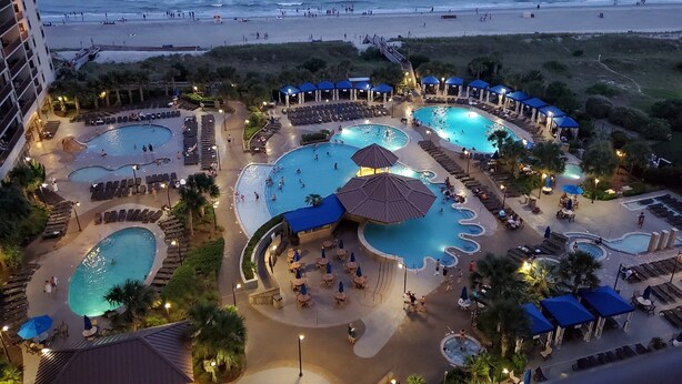 Un resort con diverse piscine, una spiaggia e vista sull'oceano.