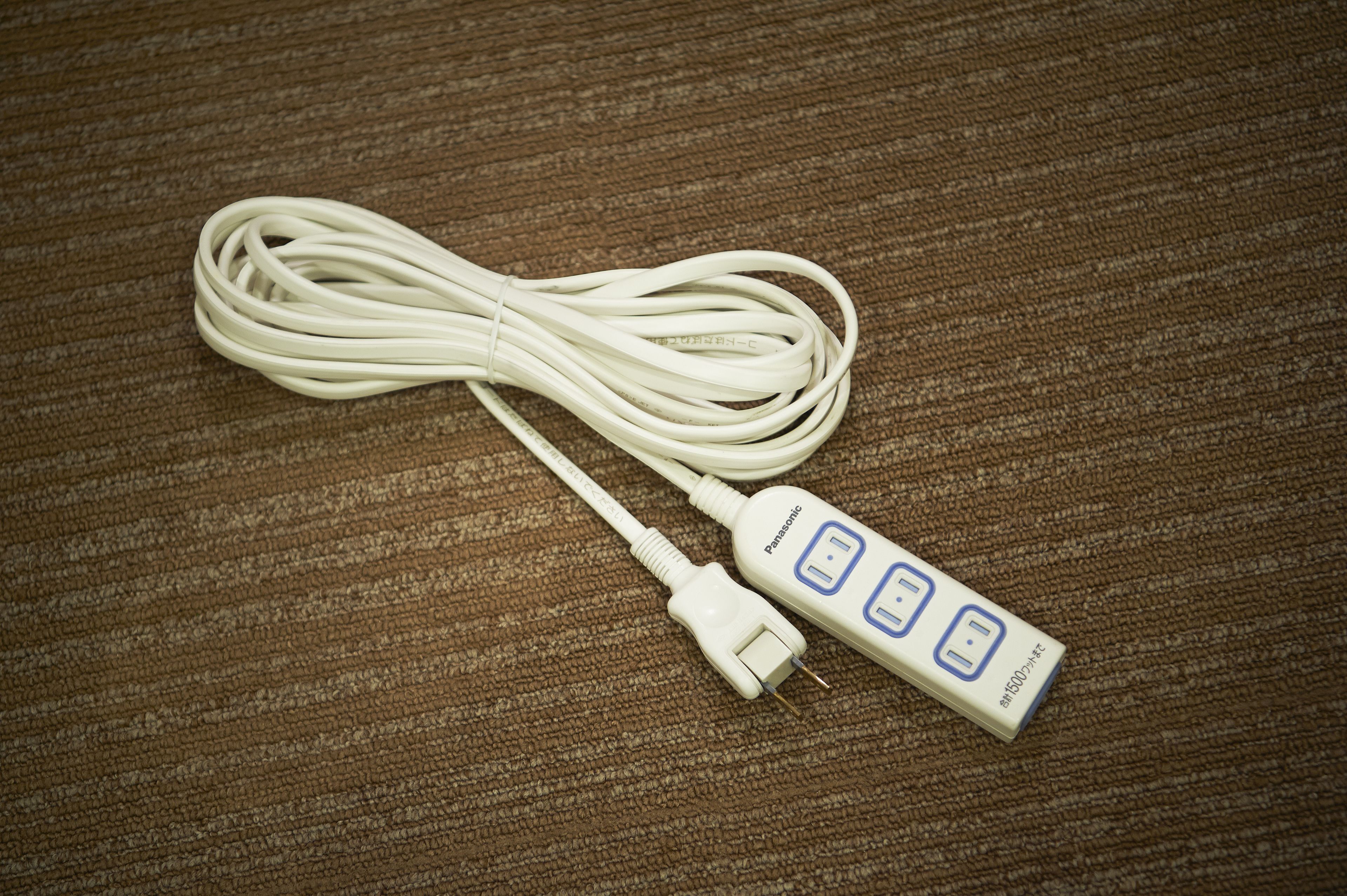 A white power adapter with a plug and a cord on a textured brown surface.