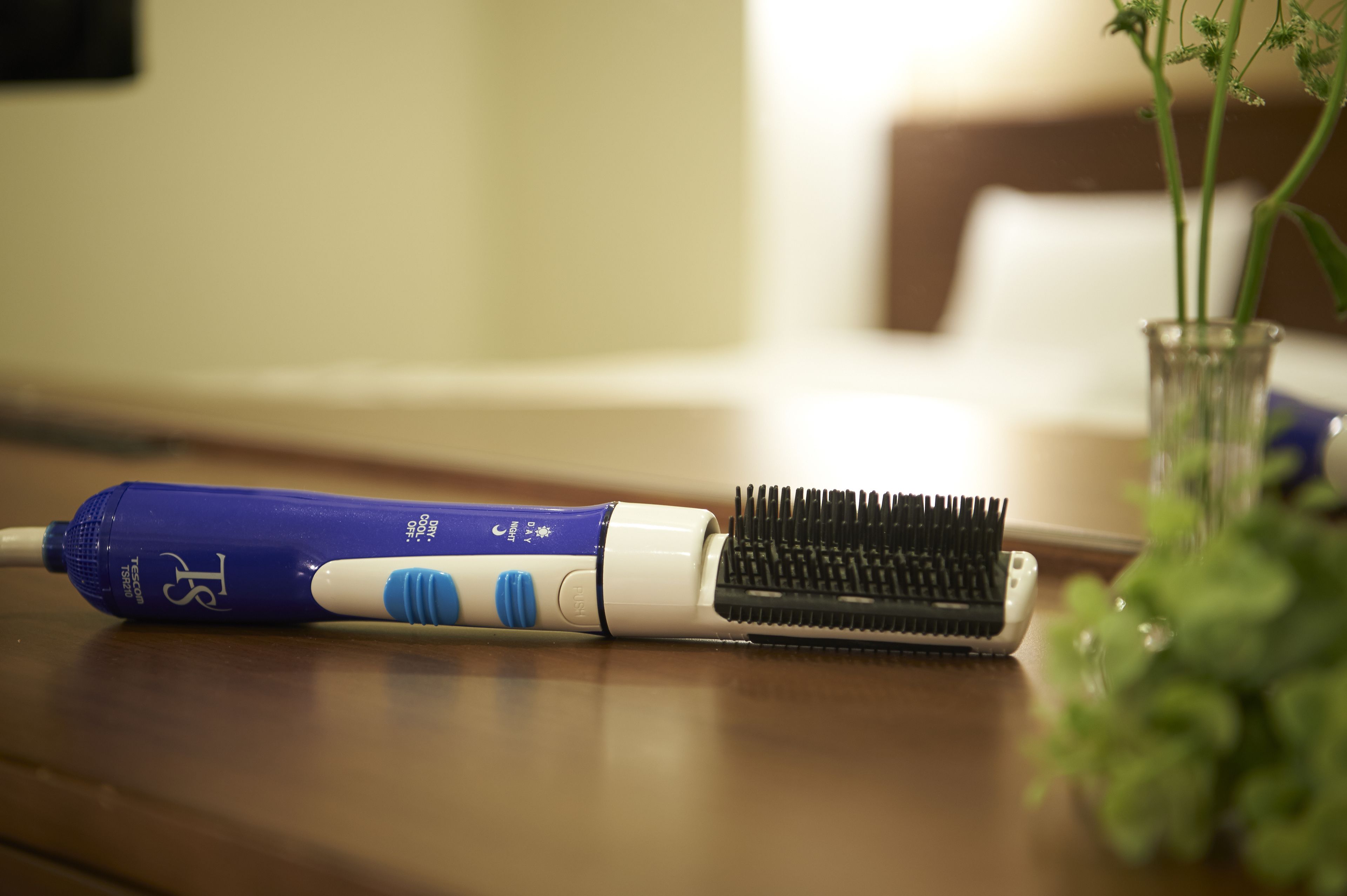 Une brosse à cheveux et un produit de soin capillaire bleu, posés sur une surface en bois.