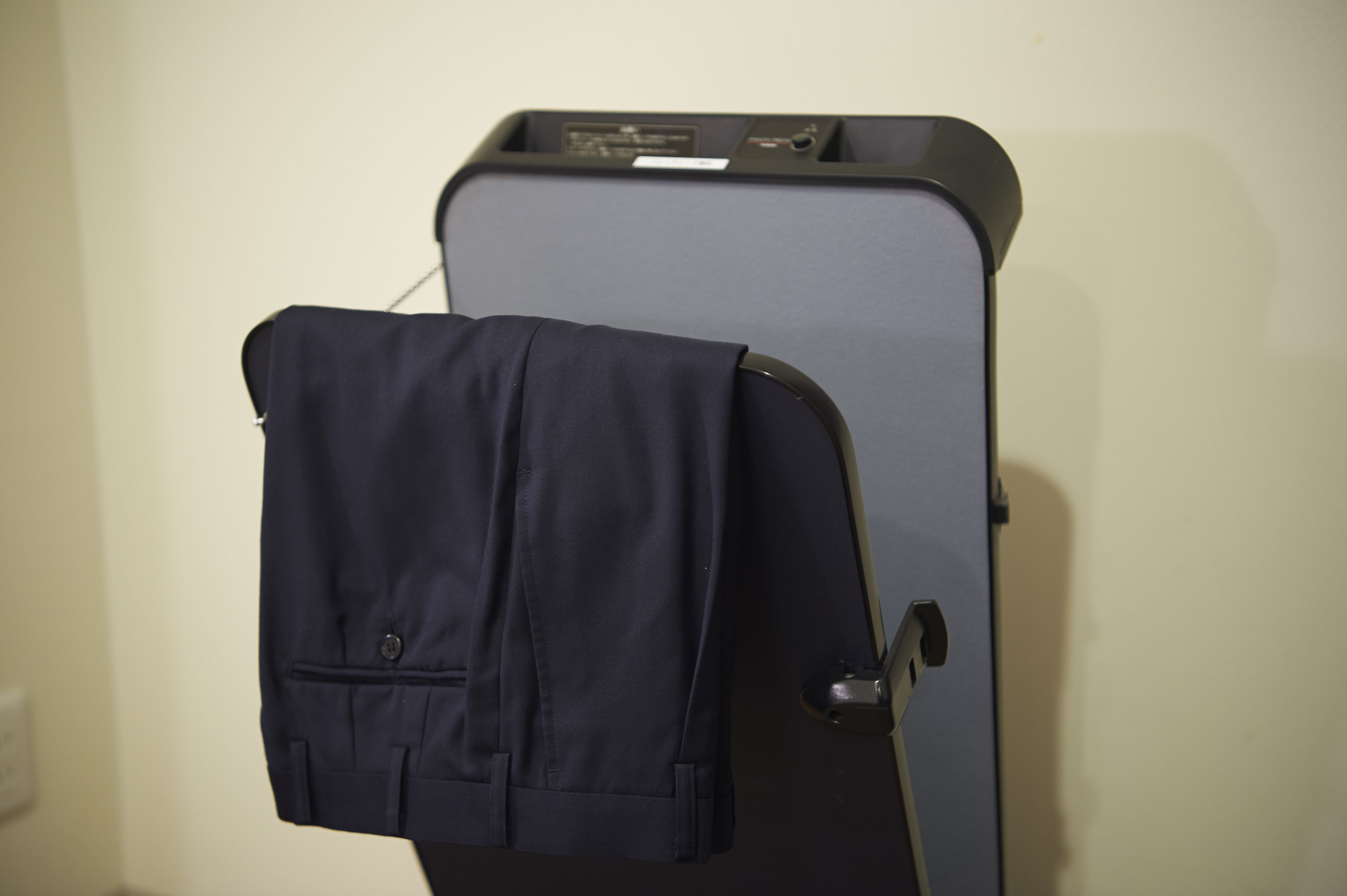 Una maleta con una chaqueta colgada, sujeta a un portaequipajes de pared.