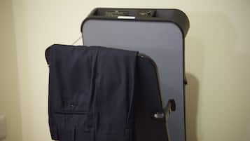 Una maleta con una chaqueta colgada, sujeta a un portaequipajes de pared.