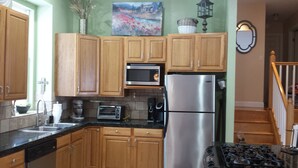 A kitchen with wooden cabinets, a stainless steel refrigerator, a microwave, a toaster, and a stove. - Charming and comfortable home away from home (Rapid City)
