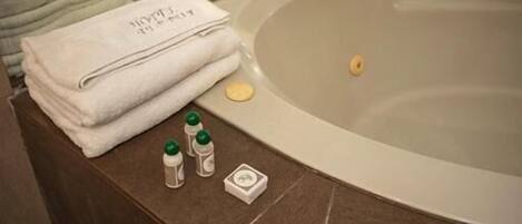 Un baño con bañera, toallas apiladas y artículos de aseo.