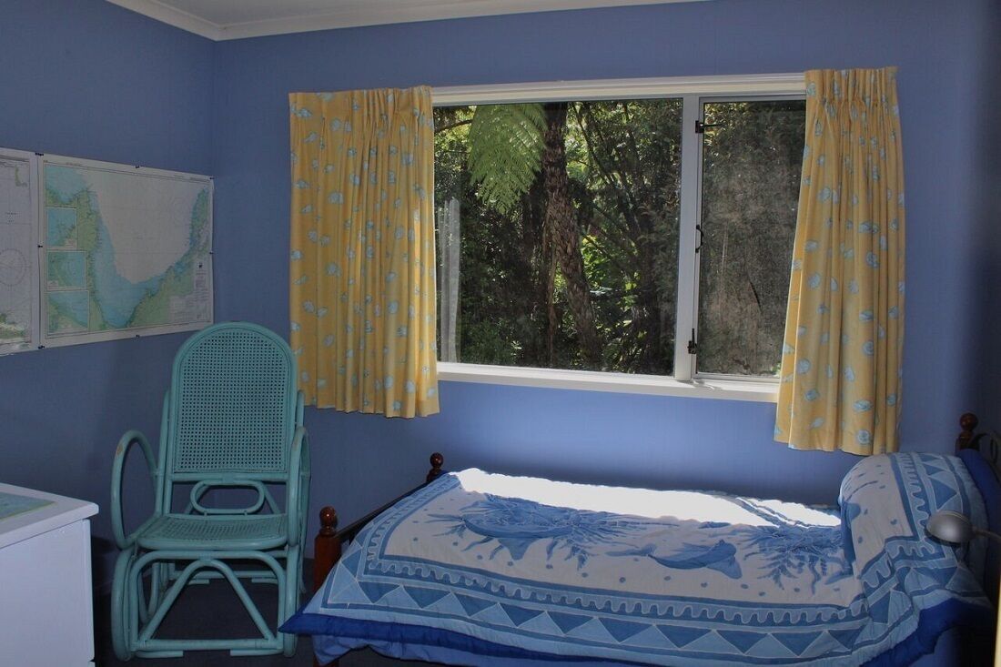 Un dormitorio con una cama, una silla, un ventanal con cortinas y un mapa en la pared.