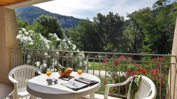 A balcony with a table, chairs, and a view of a mountainous landscape.