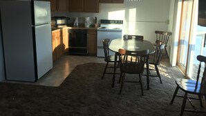 A kitchen with wooden cabinets, a refrigerator, a dishwasher, a stove, and a dining table with chairs. - 14 - Clean, Comfortable and Quiet Condo at the base of Jackson Creek Summit (Wakefield)