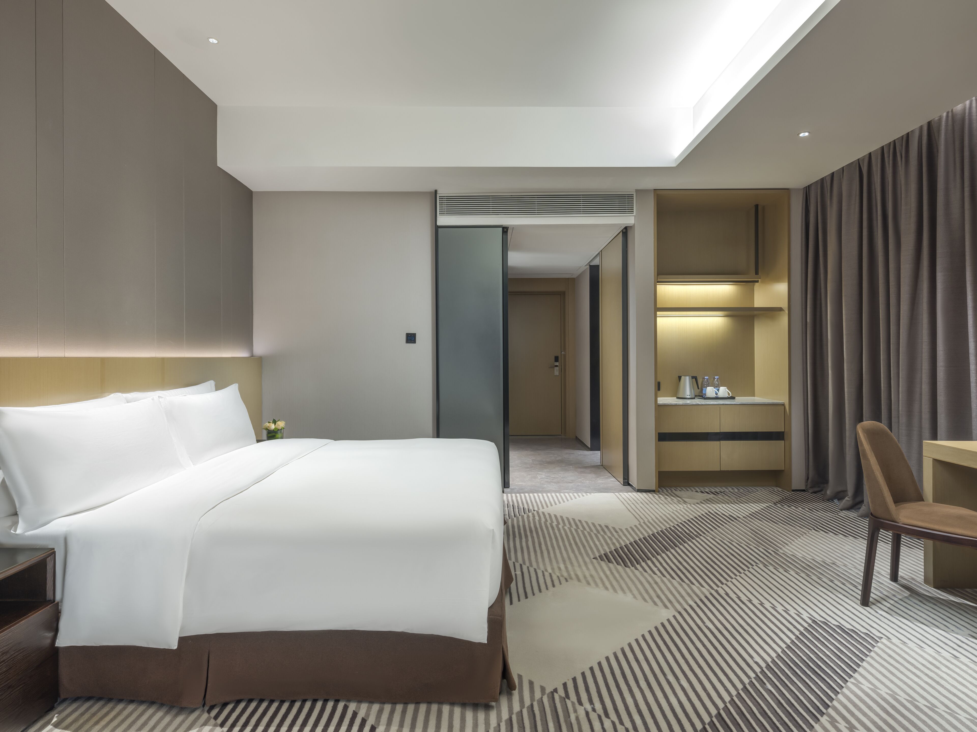 Ein modernes Hotelzimmer mit einem großen Bett, einem Schreibtisch und einem Badebereich.