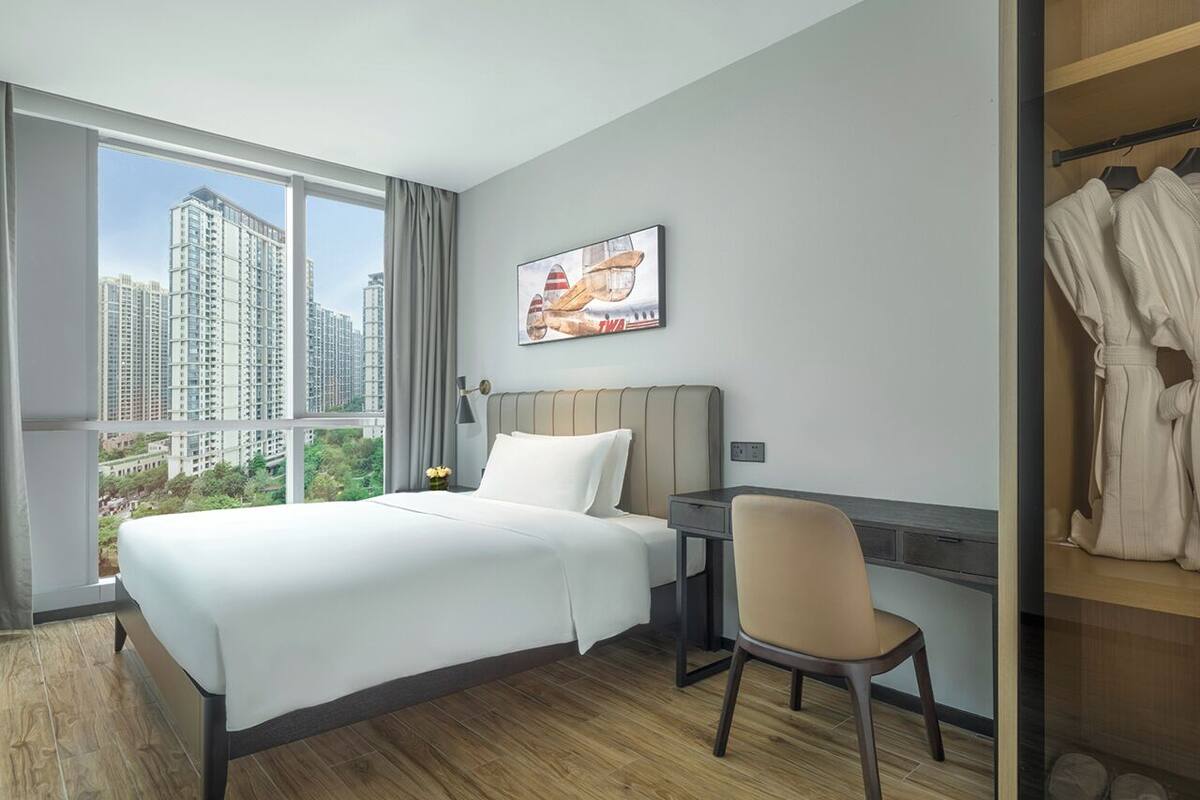 Une chambre d’hôtel avec un grand lit, un bureau, une chaise, une armoire et une vue sur la ville.
