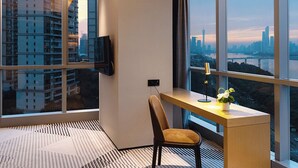 A modern hotel room with a large window, a desk, a chair, and a flat-screen TV. - La Yarda Hotel Guangzhou - Free Shuttle Bus Available during Canton Fair Period (Guangzhou)