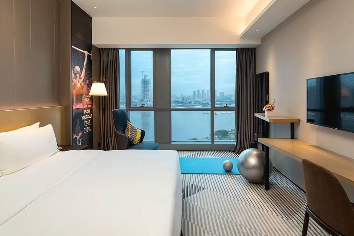 Une chambre d’hôtel avec un grand lit, un bureau, une télévision et une vue sur la ville.