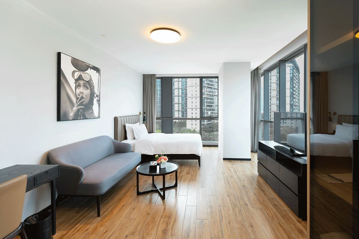 Una habitación de hotel moderna con una cama, un sofá, un escritorio y una televisión.
