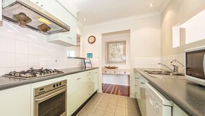 Une cuisine moderne avec des meubles blancs, une cuisinière à gaz, un four à micro-ondes et un lave-vaisselle.
