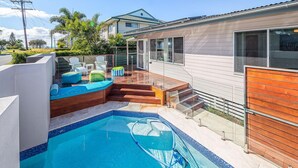 Un espace piscine moderne doté d’un jacuzzi intégré, d’une terrasse en bois et d’un coin salon extérieur.
