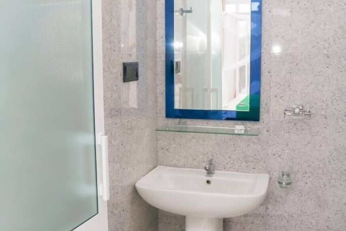 A bathroom with a white sink, a glass mirror, and a granite countertop.