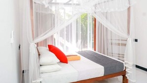 A bed with a canopy, white pillows, a red pillow, and a grey blanket. - Villa Serenity (Weligama)