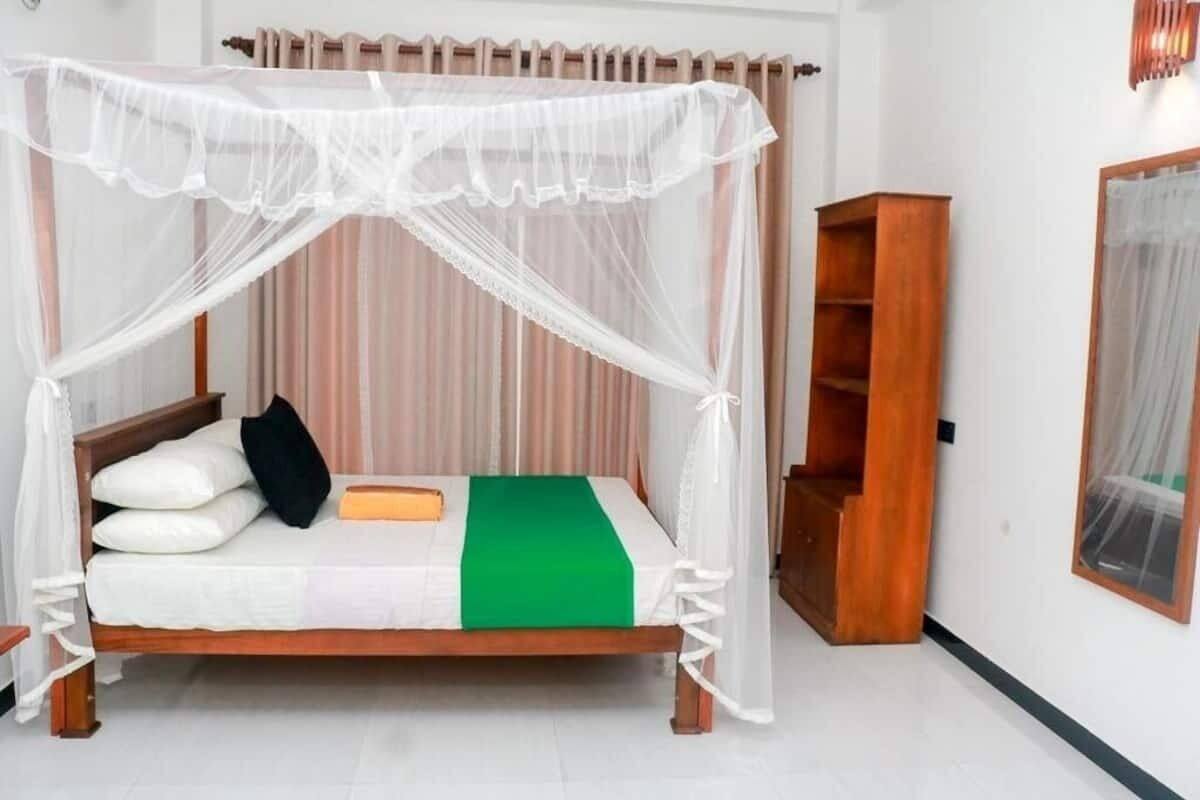 A bed with a canopy, a green blanket, and a wooden headboard.