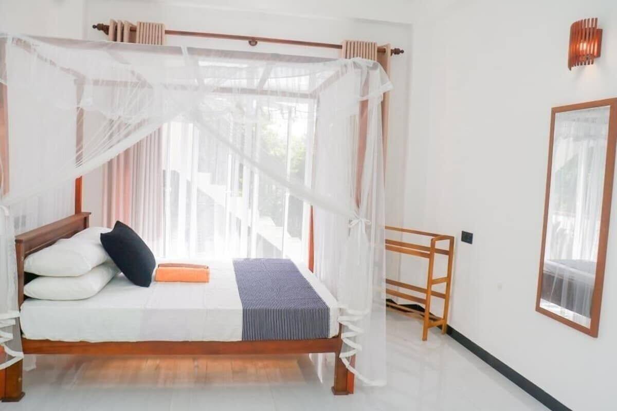 A bed with a canopy, pillows, a bedside table, and a window with curtains.