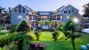Ein modernes Hotel mit einer symmetrischen Fassade, großen Fenstern und einem zentralen Innenhof mit Sitzgelegenheiten und Dekorationselementen.