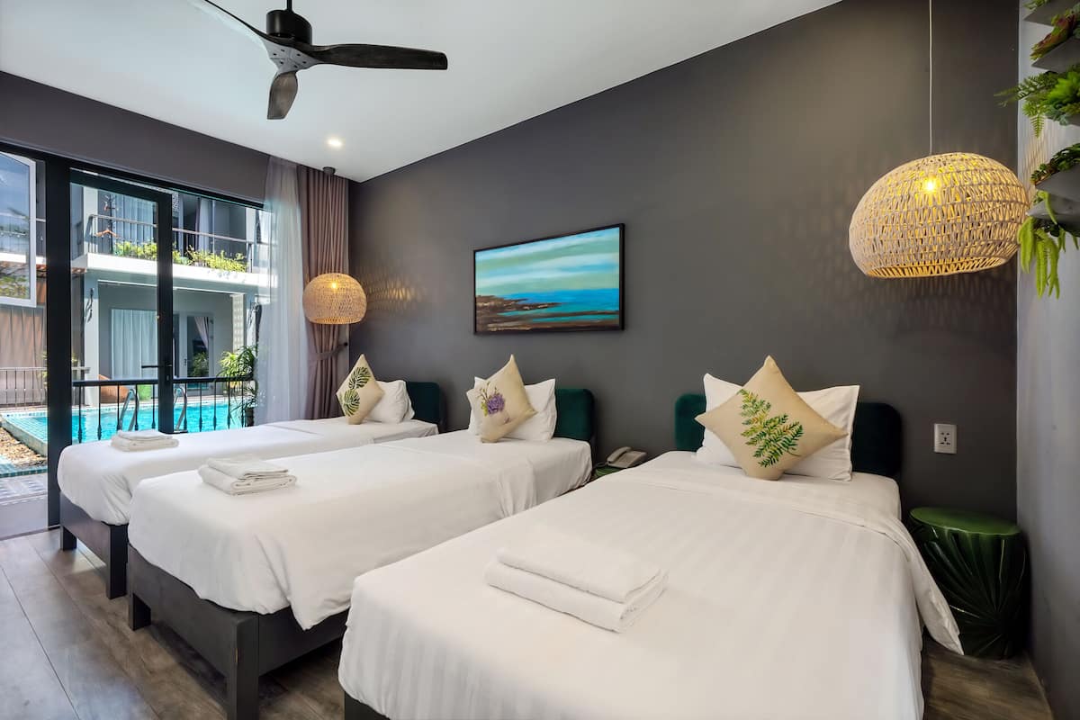 Une chambre d’hôtel moderne avec deux lits, une grande fenêtre, un ventilateur de plafond, un luminaire suspendu et une vue sur une piscine.