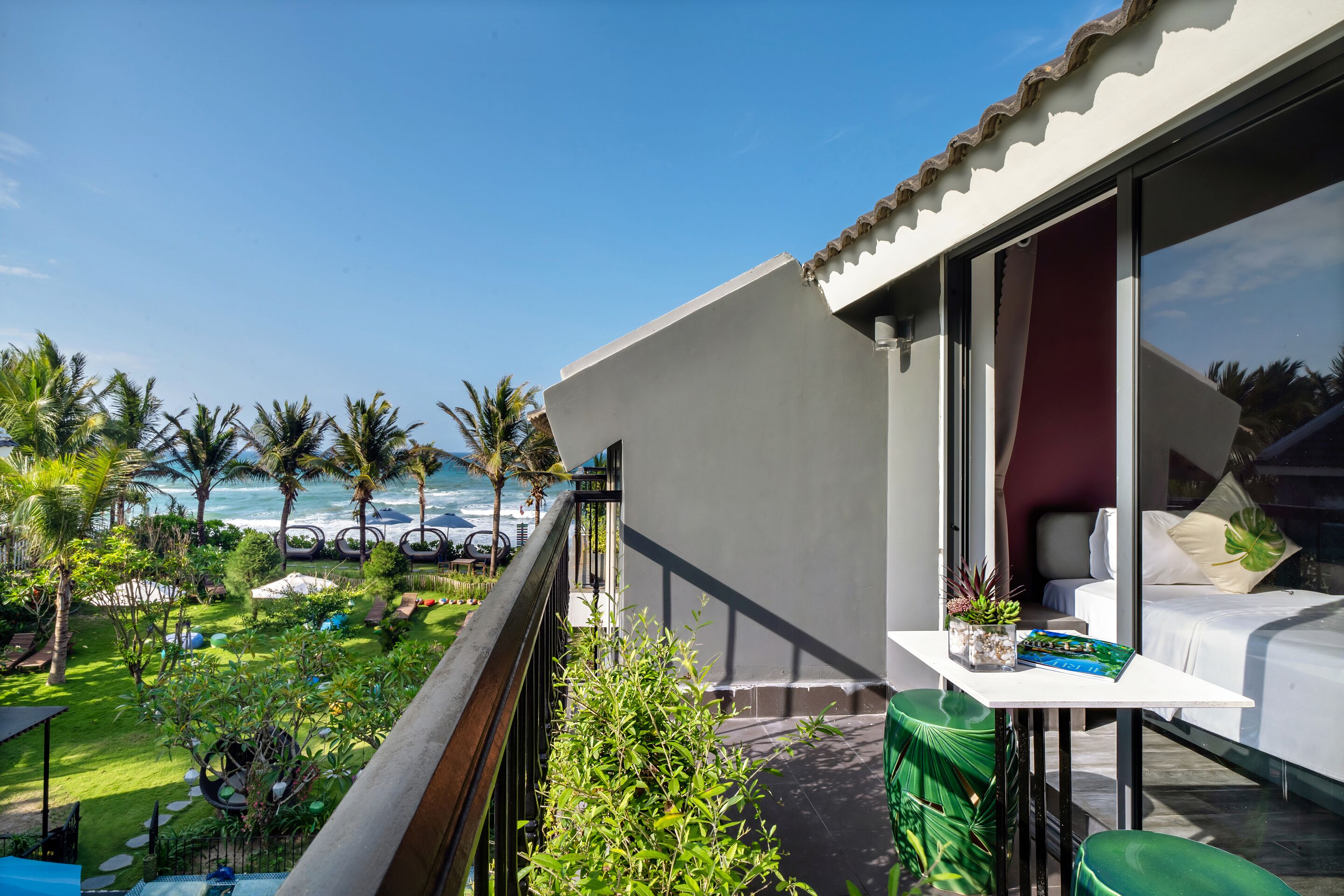 Un balcon avec vue sur l’océan, un coin repas avec une table et des chaises, et un lit avec vue.