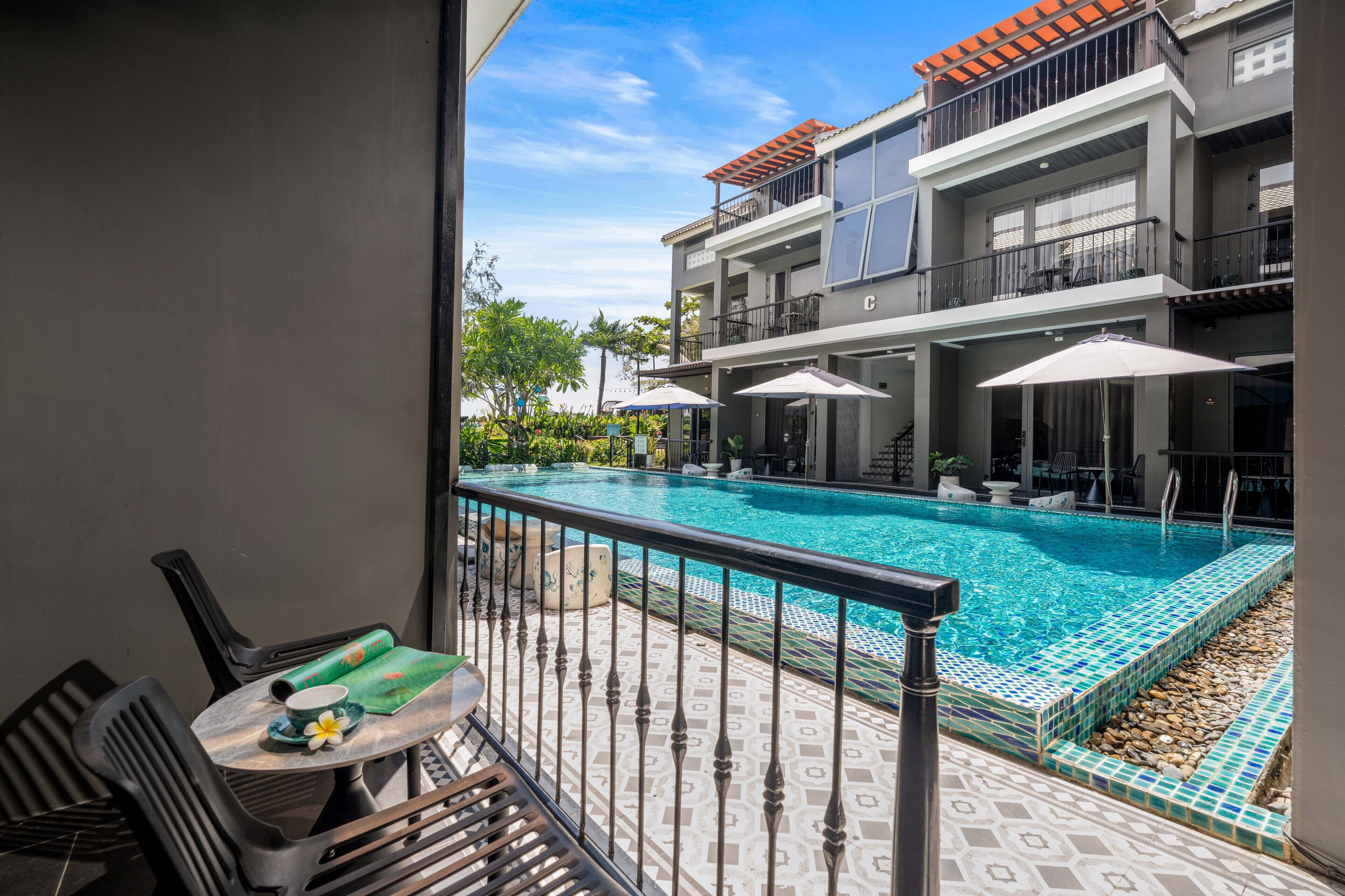 A balcony with a pool, outdoor seating, and a view of a multi-story building.