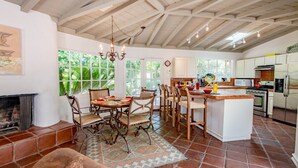 Una cocina amplia con una isla grande, armarios blancos y piso de ladrillo.